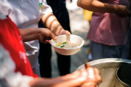 Hand begging for food from the rich's share : The beggar is waiting for food from charity aid : the concept of begging and hunger : Hunger problems of the poor have been donated food to reduce hungerの写真素材
