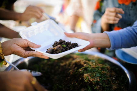 Feeding Concepts : Hand offered to donate food from a rich man Share : The concept of social sharing : Poor people receiving food from donationsの写真素材