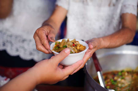 Homeless people pick up charity food from the food donors in society : The concept of the beggar problem on earth : The Hand of the Beggars receives charity food from fellow human beingsの写真素材