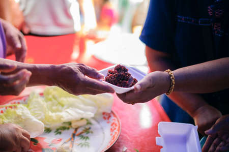 Poor people receiving food from donations : Homeless people are helped with food relief, famine relief : volunteers giving food to poor people in desperate needの写真素材