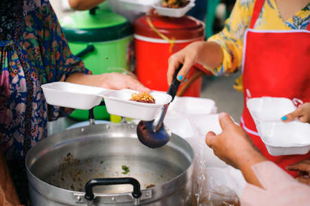 Feeding the poor to hands of a beggar : Concept of famine and social inequality : feeding food for beggar poverty concept : The society of helping to share food to the poorの写真素材