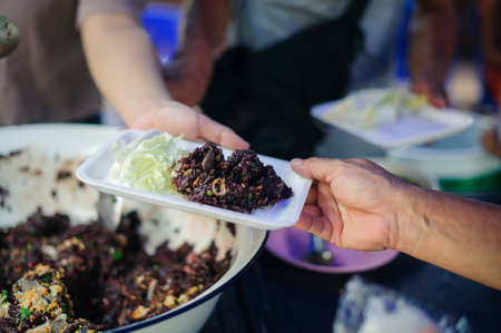 Hands of volunteers serves free food to the poor and needy in the city : The poor people bring a...