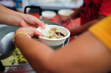 The concept of society in sharing each other : Hands of beggars accepting food from the hands of volunteers who come to help free food breaks.の写真素材