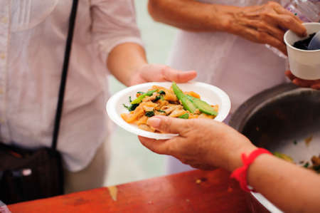 The concept of society in sharing each other : Hands of beggars accepting food from the hands of volunteers who come to help free food breaks.の写真素材