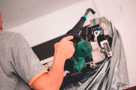 Technician man dry up and dust cleaning air Conditioner filter with electric blowersの写真素材