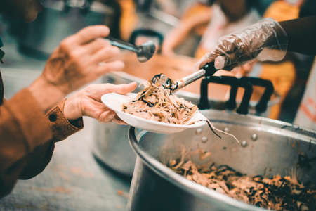 Homeless people receive delicious charity food from volunteers: concept of helping by donating food