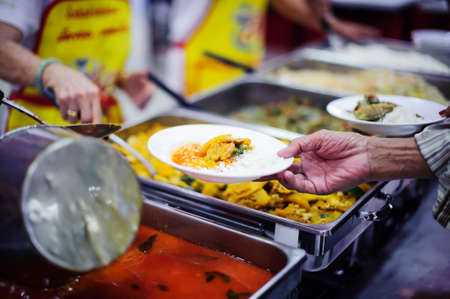 Warm food scooped from ladle into a container of the poor: the concept of givingの写真素材
