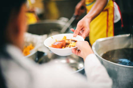 Food donation to the poor: The hands of the homeless are waiting to receive food from volunteers.の写真素材