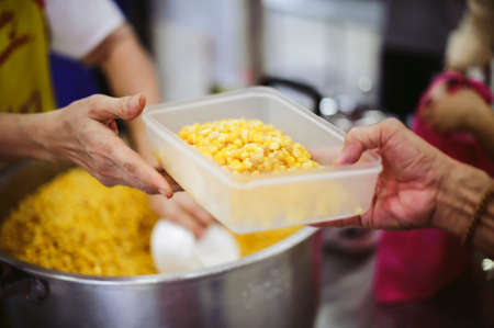 The concept of giving: Homeless people reach out to free volunteer meals from volunteers: help feed the hungry in society.の写真素材