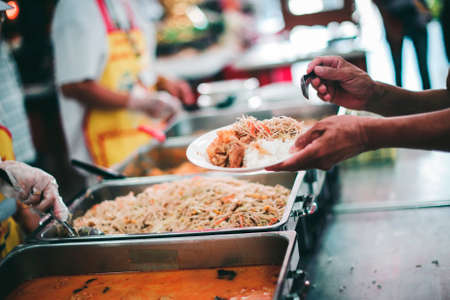 Providing free food to the poor Volunteers scooping out food to give charity to those who are...