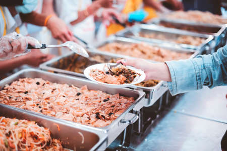 The hands of the poor receive food that volunteers share to alleviate hunger: the concept of...