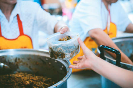Hands of beggars accepting food from the hands of volunteers