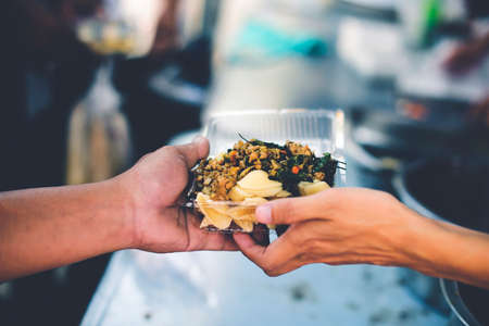 Food donation to help people in hunger relief : hands of the poor receive food from the donor's...