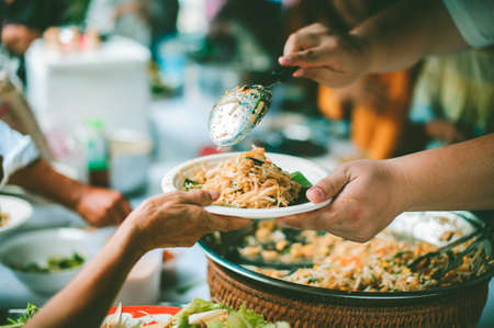 Concept of food donation : Homeless and needy people receive help, receive food from volunteersの写真素材