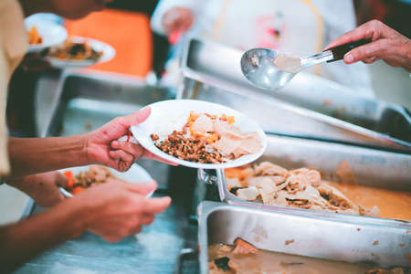 The hands of the poor get free food from the volunteers : the concept of ââsharing foodの写真素材