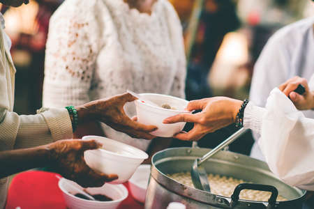 The hands of the poor get free food from the volunteers : the concept of â€‹â€‹sharing...