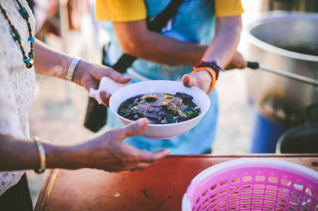 Volunteers scooping the food to share with the needy : concept of free food to beggars