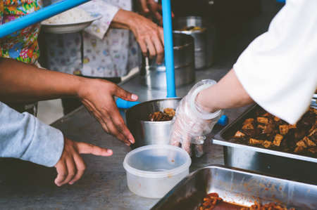 Volunteers scooping the food to share with the needy : concept of free food to beggarsの写真素材