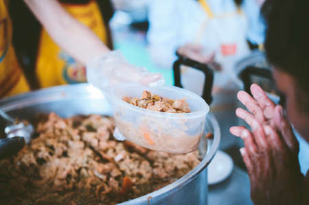 Providing free food to the poor : The hands of beggars receive donated foodの写真素材