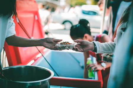 Volunteers giving food to poor people: The concept of food sharing Help solve Hunger for the homelessの写真素材