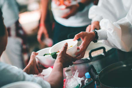 Poor people get free food from volunteers: Concept serving free food to the poorの写真素材