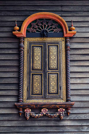 Antique carved wooden windows are decorated on old wooden walls.の写真素材