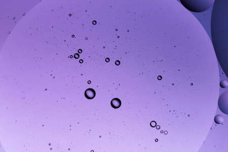 Abstract image of water droplets on glass surface reflecting with multicolored background.