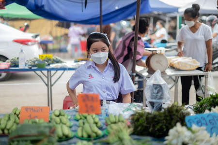 CHIANG MAI, THAILAND - JULY 30, 2021:  A woman wearing masks sits selling edamame on a stall at an open-air market in Chiang Mai, Thailand.のeditorial素材