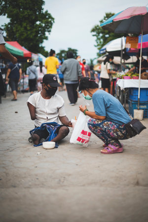 CHIANG MAI, THAILAND - JULY 30, 2021:  A woman wearing masks sits selling edamame on a stall at an open-air market in Chiang Mai, Thailand.のeditorial素材
