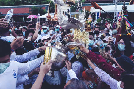 LAMPHUN, THAILAND - MAY 15, 2022: Monks and people pour auspicious water into large bowls to pay homage to the Buddha's relics during the annual Chedi That Bathing Festival at Wat Phra That Hariphunchai, Lamphun Province.のeditorial素材