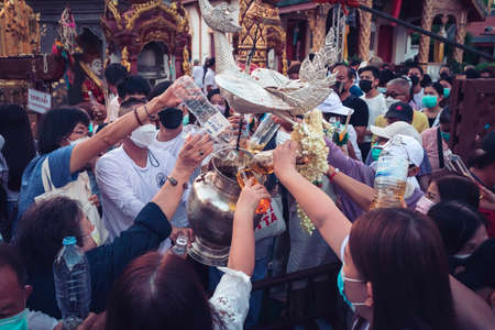 LAMPHUN, THAILAND - MAY 15, 2022: Monks and people pour auspicious water into large bowls to pay homage to the Buddha's relics during the annual Chedi That Bathing Festival at Wat Phra That Hariphunchai, Lamphun Province.のeditorial素材