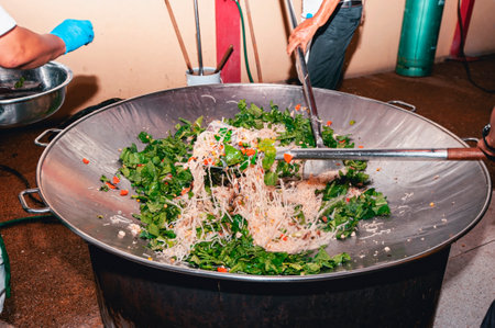 The chefs help cook food with spatulas in a large pan.の写真素材