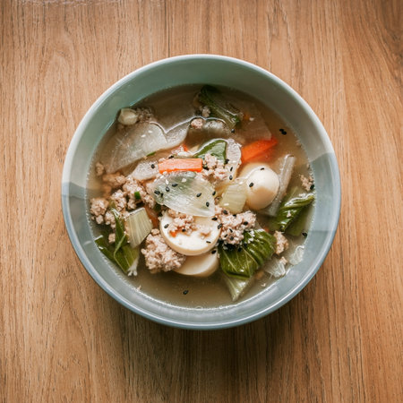 Clear soup with tofu, egg, minced pork, cabbage, carrots, onions, and sprinkled with black and white sesame seeds.の写真素材