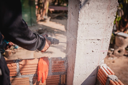 A technician uses a drill to drill a post to strengthen the adhesion of the brick wall.の写真素材