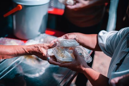 hands of the poor receive food from the donor's shareの写真素材