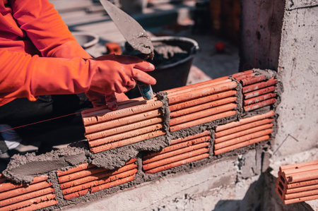A builder lays clay bricks to build a wall on a house.の写真素材