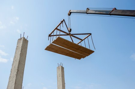 The arm of the machine lifts floor slabs in building construction.の写真素材