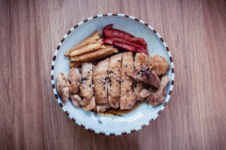 Grilled chicken with bell peppers and baby corn, topped with sauce and sprinkled with black and white sesame seeds.の写真素材