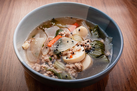 Clear soup with tofu, egg, minced pork, cabbage, carrots, onions, and sprinkled with black and white...
