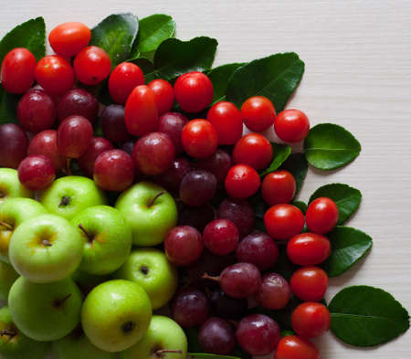 photo of fresh fruit, green apple, grape and cherry tomatoes on a white wooden boardの写真素材