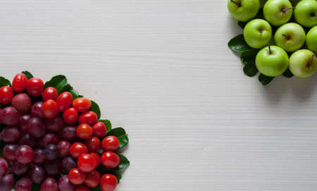 photo of fresh fruit, green apple, grape and cherry tomatoes on a white wooden boardの写真素材
