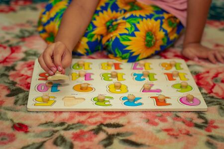 little kid playing with puzzles on wooden floor together with parent, lifestyle people concept, loving hands to each other close upの写真素材