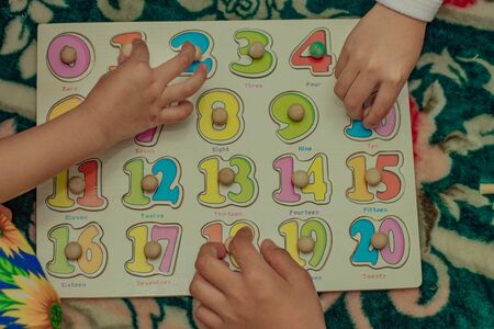 little kid playing with puzzles on wooden floor together with parent, lifestyle people concept, loving hands to each other close upの写真素材