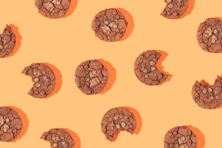 Creative pattern made with chocolate chip cookies on bright bold orange background. Happy sweet optimistic life idea. Fun food or dessert concept. Spring or summer layout.の写真素材