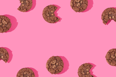 Creative pattern or frame made with chocolate chip cookies on bold bright pink background. Happy...