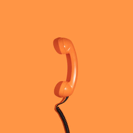 Creative layout with old phone handset on bright orange background. Retro fashion style. Minimal aesthetic telephone call concept. Spring or summer idea. Flat lay.の写真素材