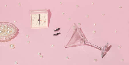 Romantic feminine fashion layout with alarm clock, false eyelashes, white pearls and martini...