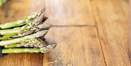 Closue-up image of bunch of green asparagus in the kitchen on wooden table. Cooking at home concept. Copy space for text.の写真素材