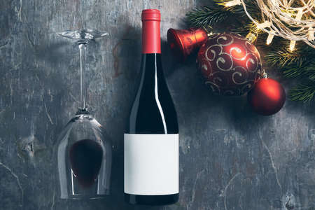 Top view of wineglass and bottle with white blank label with Christmas decorations on dark background. Wine bottle mockup with glass of wine.の写真素材