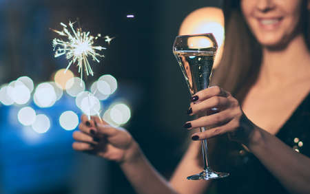 Woman celebrating New Year's Eve, toasting with champagne, holding sparkler or bengal light.の写真素材